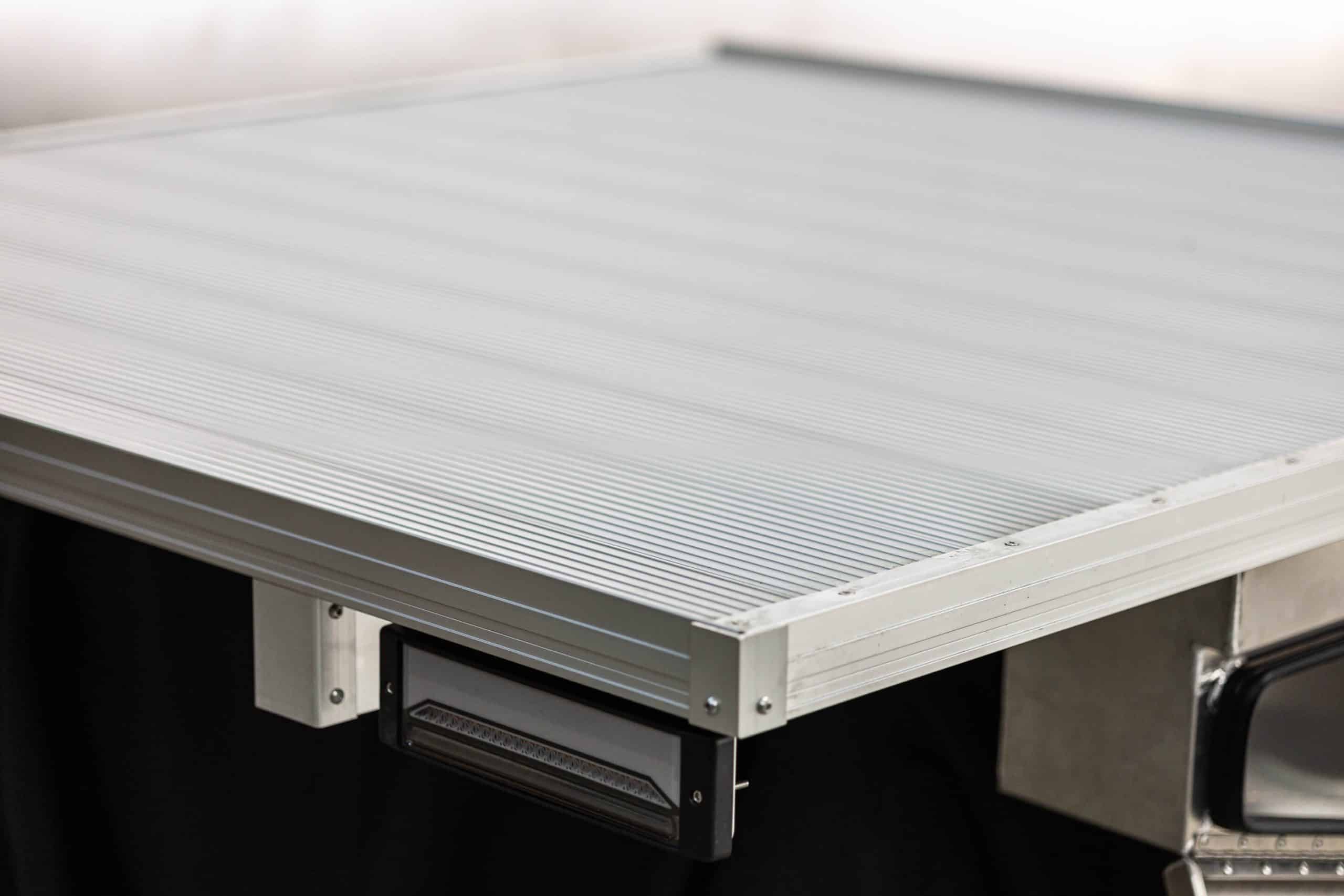 Close-up of an aluminum single cab tray with a flat surface, durable construction, and integrated LED tail light, designed for utility vehicles