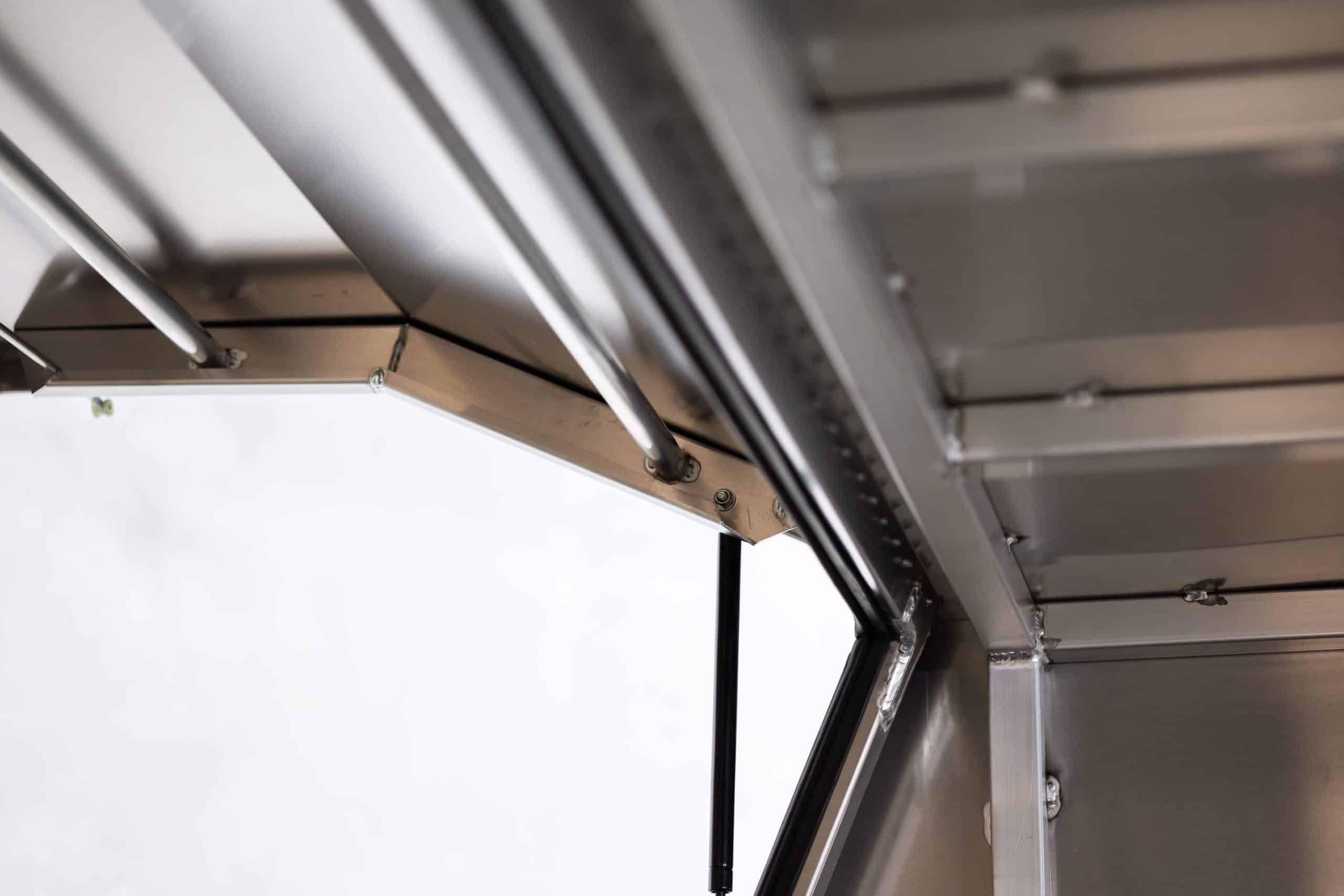 Inside view of an Oz Chivalry X1-1800 F/P 3 Doors Black UTE canopy showing the gas strut and internal frame design