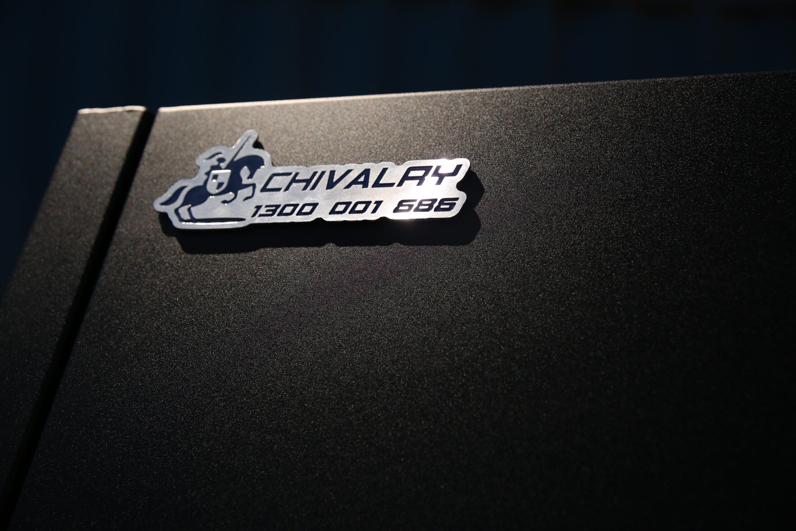 Close-up of black UTE canopy featuring engraved metal logo badge