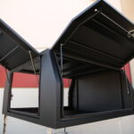 Black metal UTE canopy with upward-opening doors, offering easy access to the interior compartment