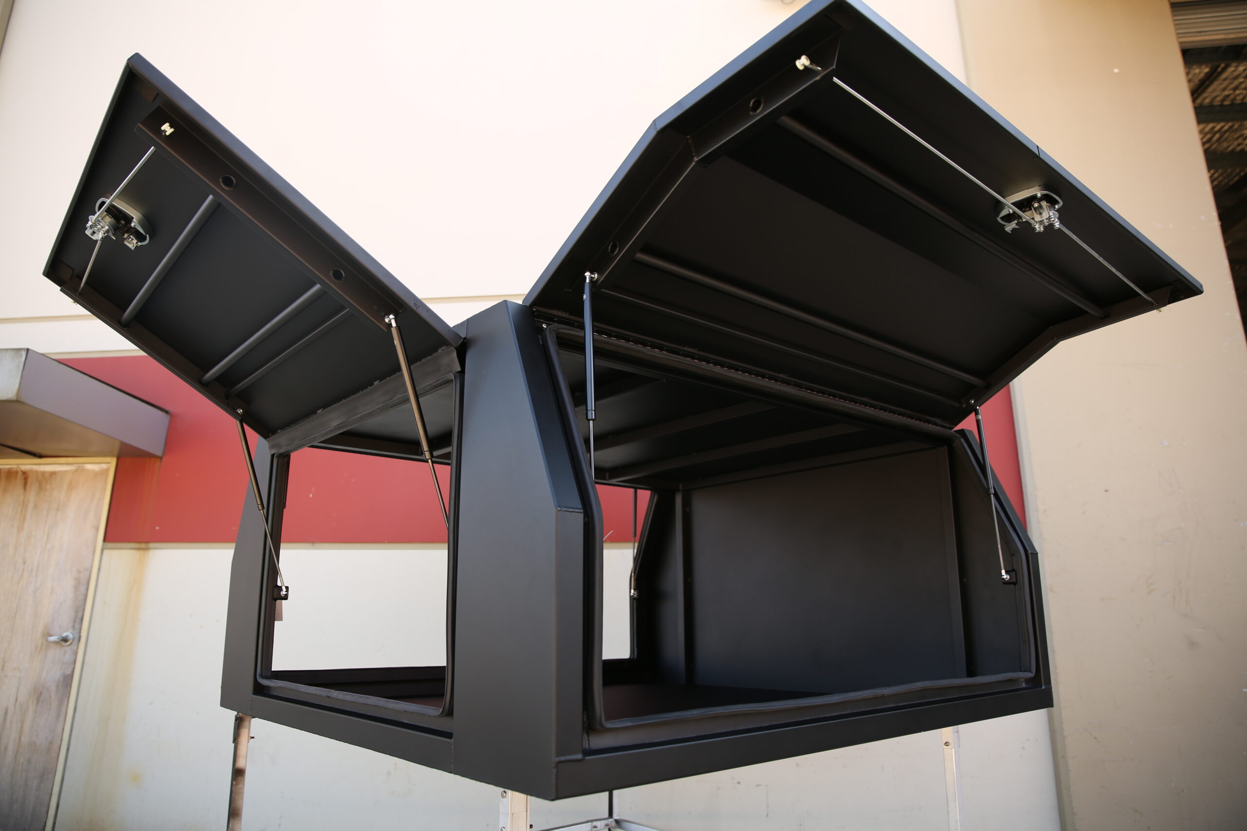 Black metal UTE canopy with upward-opening doors, offering easy access to the interior compartment